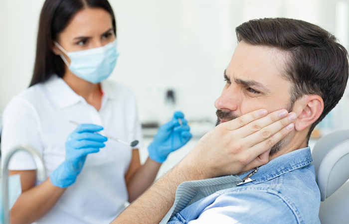 man demonstrating visible and physical tooth pain to dentist